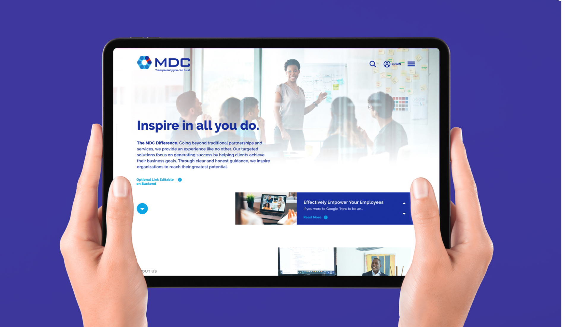 Hands holding a tablet displaying the MDC website with a banner reading "inspire in all you do." with images of professionals in a meeting room.