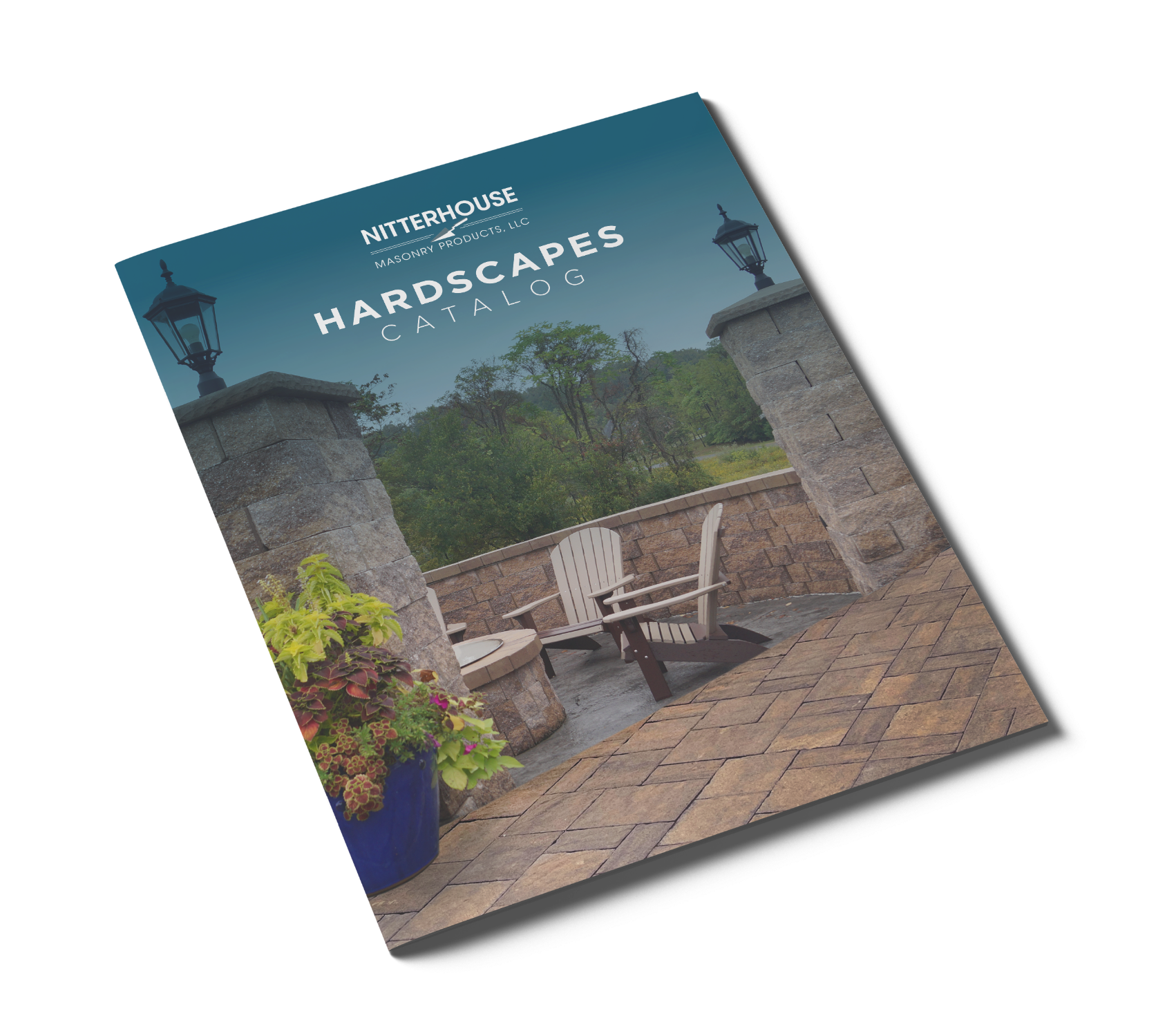 An angled view of a Nitterhouse Hardscapes catalog with a cover featuring an outdoor space with stone pillars, paving, and patio furniture, set against a natural backdrop.
