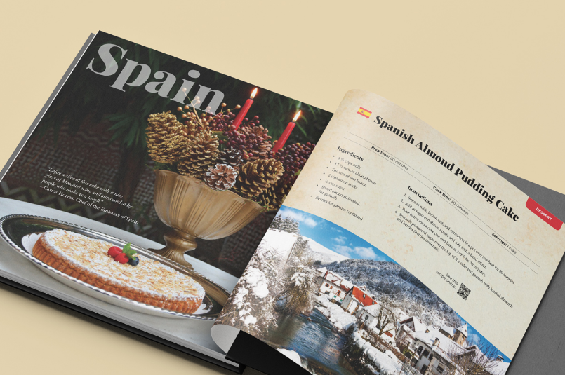 Open EU Holiday Cookbook featuring a culinary theme with a focus on Spain, showcasing a recipe for Spanish almond yule log cake alongside vibrant images of traditional Spanish food and picturesque winter scenery.