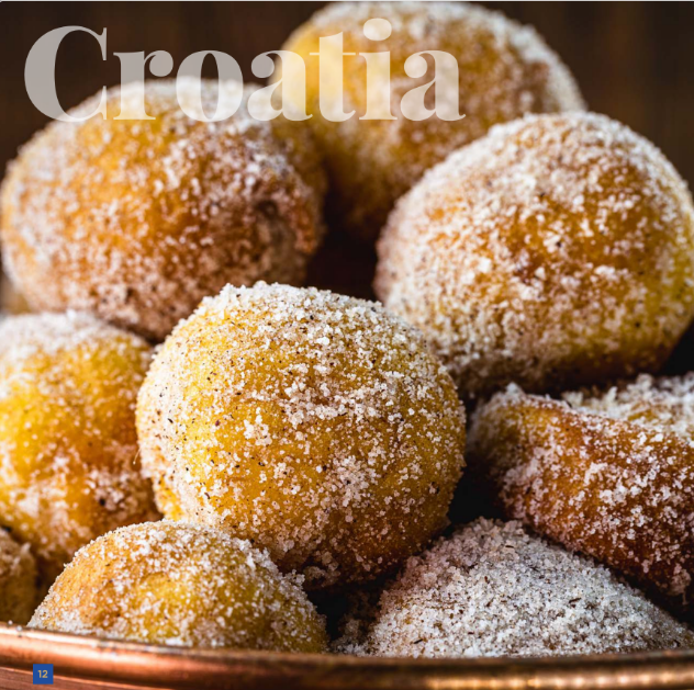 A bowl of golden-brown, sugar-dusted fritule, a traditional Croatian pastry from European cuisine, evoking the warmth of the country's hospitality and holiday cooking.