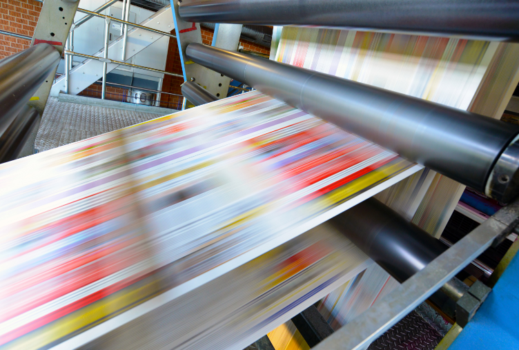 High-speed printing press in motion, producing solutions with vibrant colored material and a blur effect signifying rapid movement.