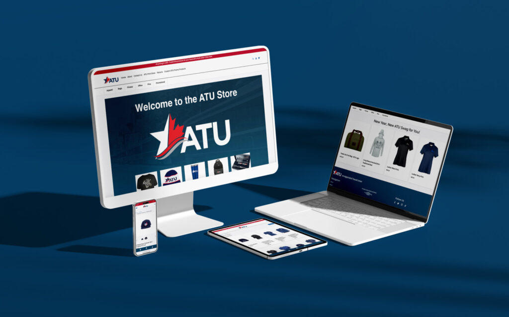 A computer monitor, laptop, tablet, and smartphone display the ATU Store's sleek storefront on a blue surface. The main screen greets visitors with a "Welcome to the ATU Store" message while apparel is showcased across other devices.